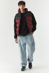 Chaleco puffer color borgoña y negro, con capucha y cuello alto.