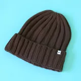 Gorro tipo beanie de tejido acanalado en color marrón, con borde doblado y etiqueta pequeña con el logo N+.