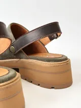 Zuecos de cuero color verde seco, con hebilla lateral y suela de goma.