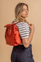 Cartera mochila de diseño versátil, color rosado, confeccionada en material sintético impermeable. Cuenta con doble asa superior, correas ajustables para usar como mochila, compartimento principal con cierre y bolsillo frontal con cierre decorado con tirador largo.