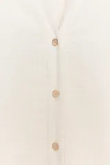 Camisa color crudo de cuello solapa y escote pico, manga larga amplia y bajo asimétrico. Cierre frontal con botones.