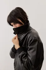 Chaqueta de cuero color negro, de corte oversize, con cierre frontal y solapas.