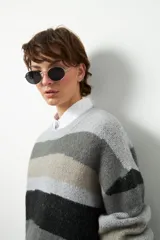 Sweater de punto con rayas horizontales en tonos beige, marrón y borgoña. De corte amplio, cuello redondo y mangas largas.