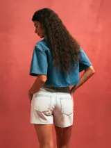 Short de jean tiro alto en color celeste claro con efecto lavado, presenta roturas desgastadas en el frente y ruedo desflecado.