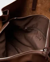 Cartera grande marrón de símil cuero con textura efecto cocodrilo, diseño estructurado tipo tote con doble asa larga de hombro y detalles de tiras laterales.