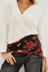 Pañuelo cuadrado con estampado floral sobre fondo oscuro, confeccionado en una mezcla de cupro y modal. Presenta aplicaciones de lentejuelas que resaltan los motivos botánicos en tonos rojos y rosados.