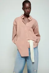 Camisa de cuello solapa y manga larga con estampado de rayas verticales. Presenta un bolsillo de plastrón en el delantero, cierre frontal con botones y detalle de botones en la espalda. Su diseño cuenta con un bajo asimétrico y aberturas laterales.