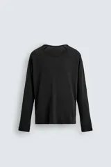 Camiseta negra de corte relaxed fit, confeccionada en tejido ligero con algodón. Presenta cuello redondo y manga ranglán larga.