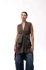 Chaleco de diseño fluido con escote cruzado y lazo ajustable en la cintura. Presenta un corte largo y versátil, ideal para superponer en diferentes looks.