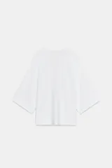 Top fluido de punto liso en color blanco, con escote en V pronunciado y mangas cortas amplias.