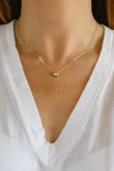 Collar minimalista con cadena fina de acero quirúrgico con baño de oro y un dije central de cristal redondo engastado en bisel.