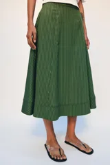 Falda midi de tiro alto, confeccionada en hilatura con mezcla de viscosa, con diseño de rayas verticales en tonos verdes y negros. Presenta corte evasé con bajo acabado y cierre con cremallera oculta en la costura.