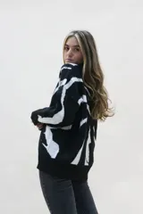 Sweater negro con estampado abstracto en color blanco, de corte holgado y mangas largas.