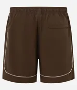 Bermuda deportiva color marrón con piping en color crema, confeccionada en poliamida de secado rápido. Cuenta con cintura elástica con cordón ajustable y bolsillos laterales.