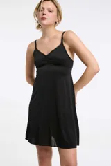 Camisón negro de microfibra, con tirantes finos regulables, escote corazón con detalle de encaje y frunce frontal, y falda corta fluida.