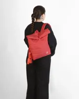 Mochila acolchada color beige con cierre superior enrollable y hebilla.