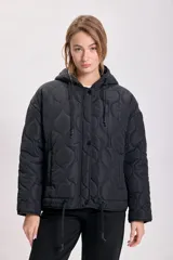 Campera capitoneada negra con diseño acolchado, cierre frontal con botones a presión, capucha con cordón ajustable y cordón en el ruedo.
