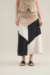 Falda larga de lino con diseño de cortes diagonales en bloques de color blanco, beige y tostado, de corte evasé y caída fluida.