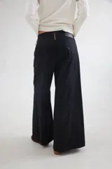 Pantalón de tiro medio-alto con piernas anchas y corte recto. Presenta cierre frontal con botón, bolsillos laterales y detalles de costuras verticales. Confeccionado en tencel.