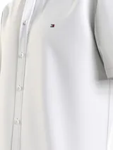Camisa blanca de manga corta confeccionada en popelín de puro algodón, con cuello abotonado, corte regular y logo de Tommy Hilfiger bordado en el pecho.