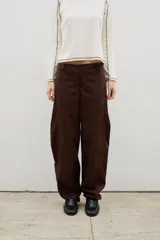 Pantalón de gabardina color marrón, con corte holgado tipo barrel, tiro medio y costuras laterales marcadas.