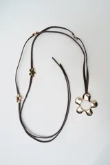 Cinturón fino de cuero sintético marrón, con diseño de flores metálicas doradas distribuidas a lo largo de la tira y una hebilla grande en forma de flor con centro hueco.