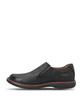 Zapato tipo mocasín Hush Puppies modelo Oregon, confeccionado en cuero negro con textura granulada. Presenta un diseño slip-on con elásticos laterales, costuras reforzadas y una suela de goma EVA que proporciona flexibilidad y aislamiento térmico.