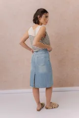 Pollera midi de denim celeste claro, de tiro medio y corte recto. Cuenta con bolsillos traseros, abertura central en la parte posterior y cierre frontal con botón y cremallera.