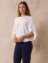 Blusa de gasa con estampado geométrico en tonos negro, gris y celeste. Tiene cuello redondo y mangas 3/4 amplias con abertura y botón.