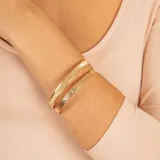 Esclava rígida de oro 18k con acabado satinado y diseño de cinta plana. Presenta una textura fina y elegante en toda su superficie.