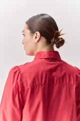 Camisa blanca de algodón, de calce relajado, con cuello camisero, frente abotonado y mangas largas abullonadas.