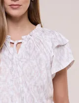 Blusa de calce suelto en color beige con estampado geométrico, cuello redondo fruncido con escote en V y cordel para anudar, y mangas cortas con doble capa de volante.