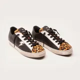 Zapatillas bajas de cuero vacuno negro con puntera de cuero con pelo de leopardo. Aplique lateral de rayo de cuero blanco con contorno dorado. Cordones de algodón encerado y suela de caucho con banda cosida.