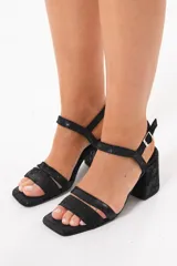 Sandalias de taco ancho color negro, con diseño de doble tira delantera, punta cuadrada y tira ajustable con hebilla en el tobillo.