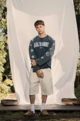 Crewneck de manga larga color gris oscuro con efecto lavado, estampado frontal con el texto "ENDLESS SUMMER" y estrellas estampadas a lo largo de las mangas.