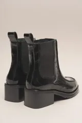 Bota Chelsea de cuero charol negro, con elástico lateral, punta cuadrada y taco bajo.
