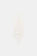 Body de cuello halter con espalda descubierta, confeccionado en poliamida. Presenta un diseño drapeado en los laterales y una abertura frontal con detalle metálico. Posee cierre con botones a presión en la parte inferior y lazada en el cuello.