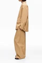 Chaqueta color tostado con diseño de rayas diplomáticas verticales en tono claro, solapas de muesca, cierre frontal de dos botones y bolsillos laterales con solapa.