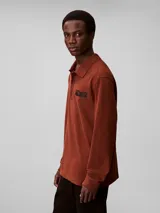 Chomba de manga larga Calvin Klein color marrón, con cuello clásico, cierre frontal con botones y logo bordado en el pecho.