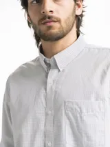 Camisa celeste y blanca a cuadros con cuello abotonado, manga larga y bolsillo en el pecho.