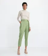 Pantalón carrot de Marfinno en color verde, confeccionado en mezcla de viscosa y lino. Presenta tiro medio, cierre frontal con cremallera, bolsillos, costuras frontales marcadas y detalle de cinturón incorporado con hebilla circular.