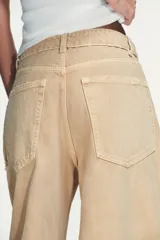Jeans de tiro medio y corte ancho, confeccionados en denim con lavado estilo vintage de efecto desgastado. Presentan diseño de doble cinturilla superpuesta, cinco bolsillos tradicionales, trabillas para cinto y cierre frontal con cremallera y botón metálico.