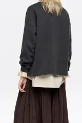 Sudadera de corte recto y holgado, con cuello redondo y manga larga. Presenta un estampado artístico de paisaje montañoso con un ciervo en el frente.