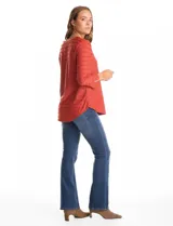 Blusa de tejido shaggy color terracota, con cuello a la base, mangas tres cuartos con tajo lateral en el puño y ruedo redondeado con largo posterior asimétrico.