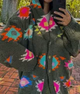 Saco tejido a mano de color negro, con diseño geométrico multicolor, cuello smoking y cierre frontal con dos botones.