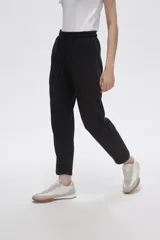 Pantalón tipo babucha de color negro, confeccionado en tejido con felpa, con cintura elástica ajustable mediante cordón y puños en los tobillos.