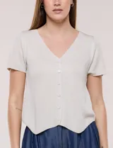 Cardigan corto de tejido de punto fino con hilo brillante de lurex y destellos metalizados. Presenta escote en V pronunciado, mangas cortas, cierre frontal con botones a tono y ruedo con terminación en pico en el frente.