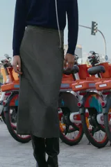 Falda midi tubo jaspeada en color gris oscuro, de tiro alto, con abertura en la espalda y cierre trasero con cremallera oculta.