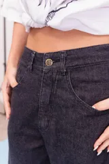 Pantalón de jean de corte wide leg en color gris oscuro, con tiro medio y cierre frontal con botón y cremallera.