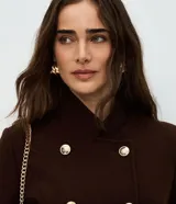 Campera de paño color marrón, con diseño estructurado de doble abotonadura con seis botones metálicos dorados. Presenta cuello alto, mangas largas y corte recto.
